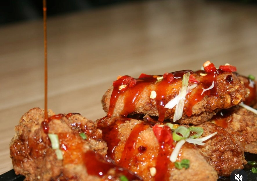 Crispy wings being finished with Authentic-Ate signature sauce